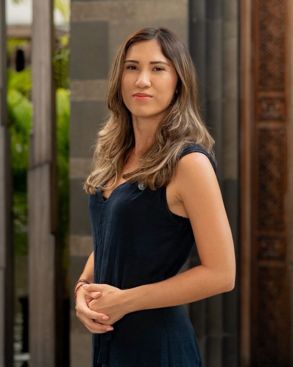 Tanisha Lo standing between stone columns and carved timber, hands clasped